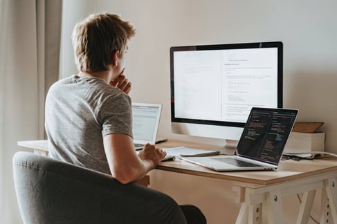 Adapting Evolving Remote Work From Home WFH young man sitting at desk looking at computers