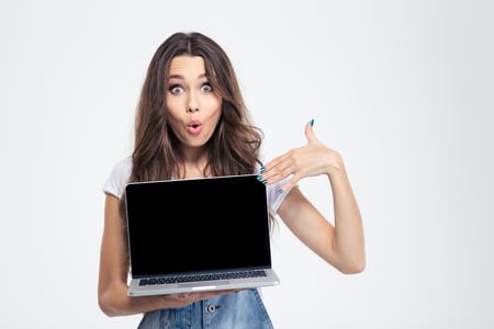 Portrait of a happy woman pointing finger on blank laptop computer screen isolated on a white background