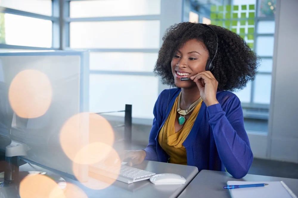 Portrait of a smiling customer service representative with an afro at the computer using headset-1-1
