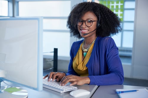 Portrait of a smiling customer service representative with an afro at the computer using headset-2