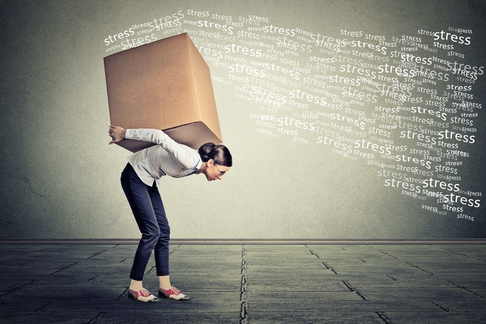 Stressed woman carrying on her back shoulders large box