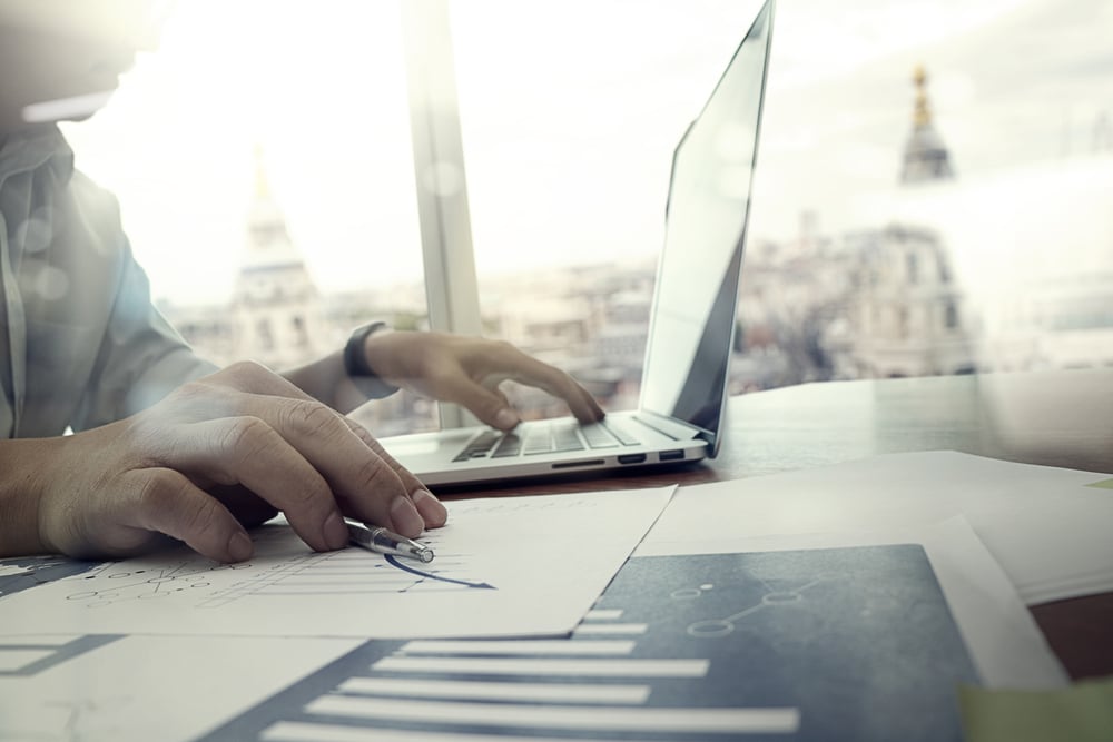 business documents on office table with laptop computer and graph financial diagram and man working in the background-1