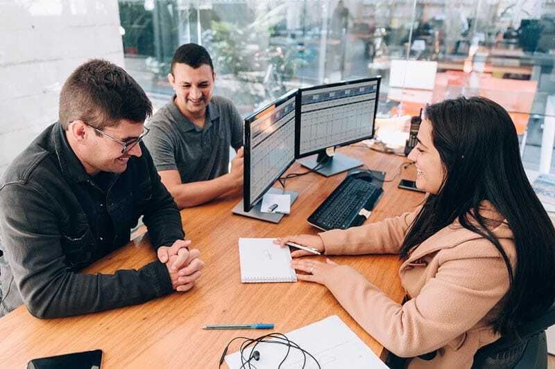 managed it services financial banks credit unions coworkers having meeting sitting at desk smiling with desktop monitor