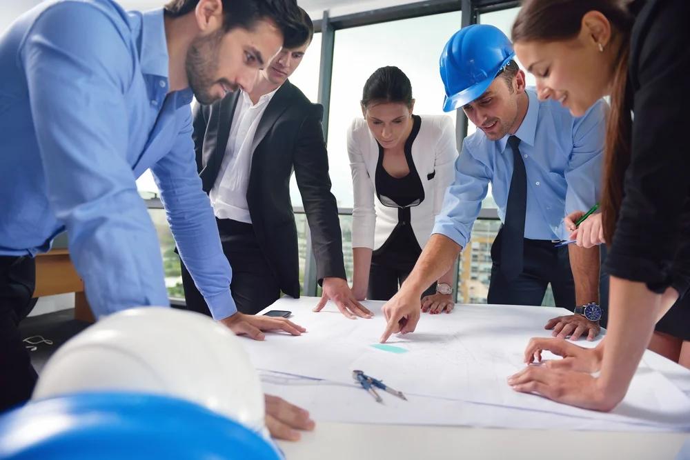business people group on meeting and presentation  in bright modern office with construction engineer architect and worker looking building model and blueprint planbleprint plans (2)
